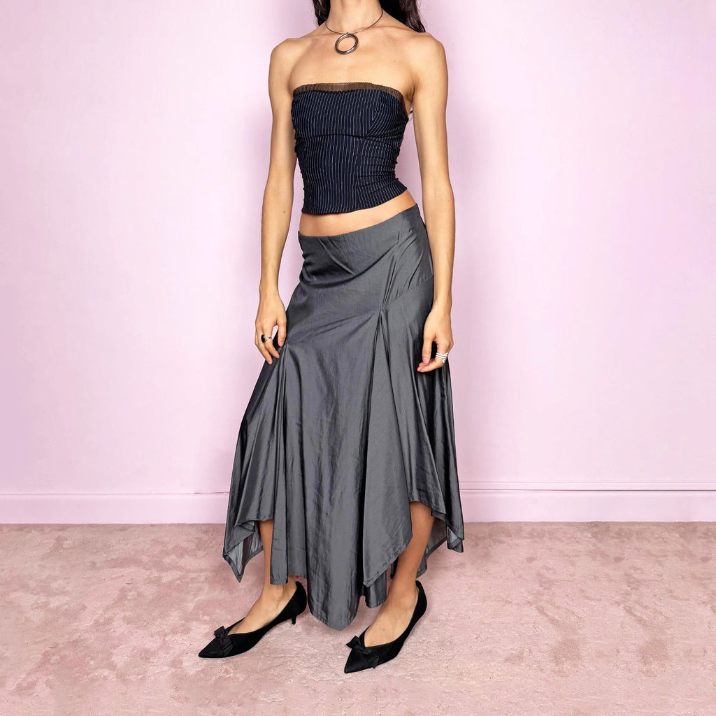 Vintage 2000s silver gray midi skirt with an avant garde asymmetric deconstructed design and fluid godet panel details. Features a glossy satin-like finish, no stretch structure, and back zip closure. Can be worn low rise for size S or mid rise for size M. Perfect for formal, statement, or evening wear. Made from a polyester viscose blend. Excellent vintage condition.