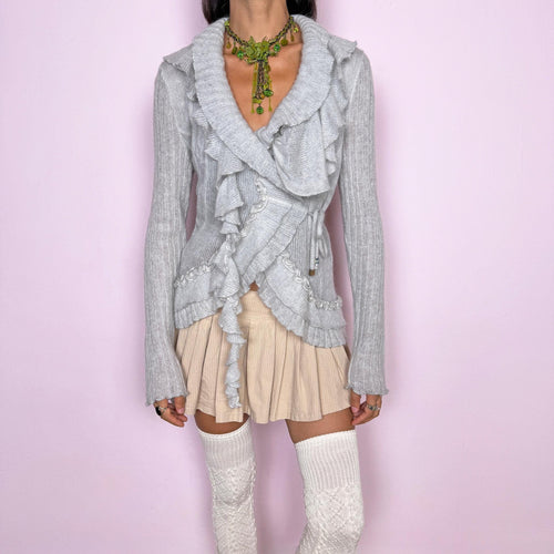 Vintage 2000s light gray wrap cardigan featuring a wrap-front silhouette with adjustable tie fastening, allowing the width and fit to be easily adjusted at the waist. Finished with cascading ruffle trim throughout, long sleeves and delicate textured knit detailing. The airy mohair blend, soft gray tone and sculptural ruffles give it a dreamy, romantic feel. By an Italian designer, made in Italy from a soft 20% mohair, 40% polyamide and 40% acrylic blend. Excellent vintage condition.