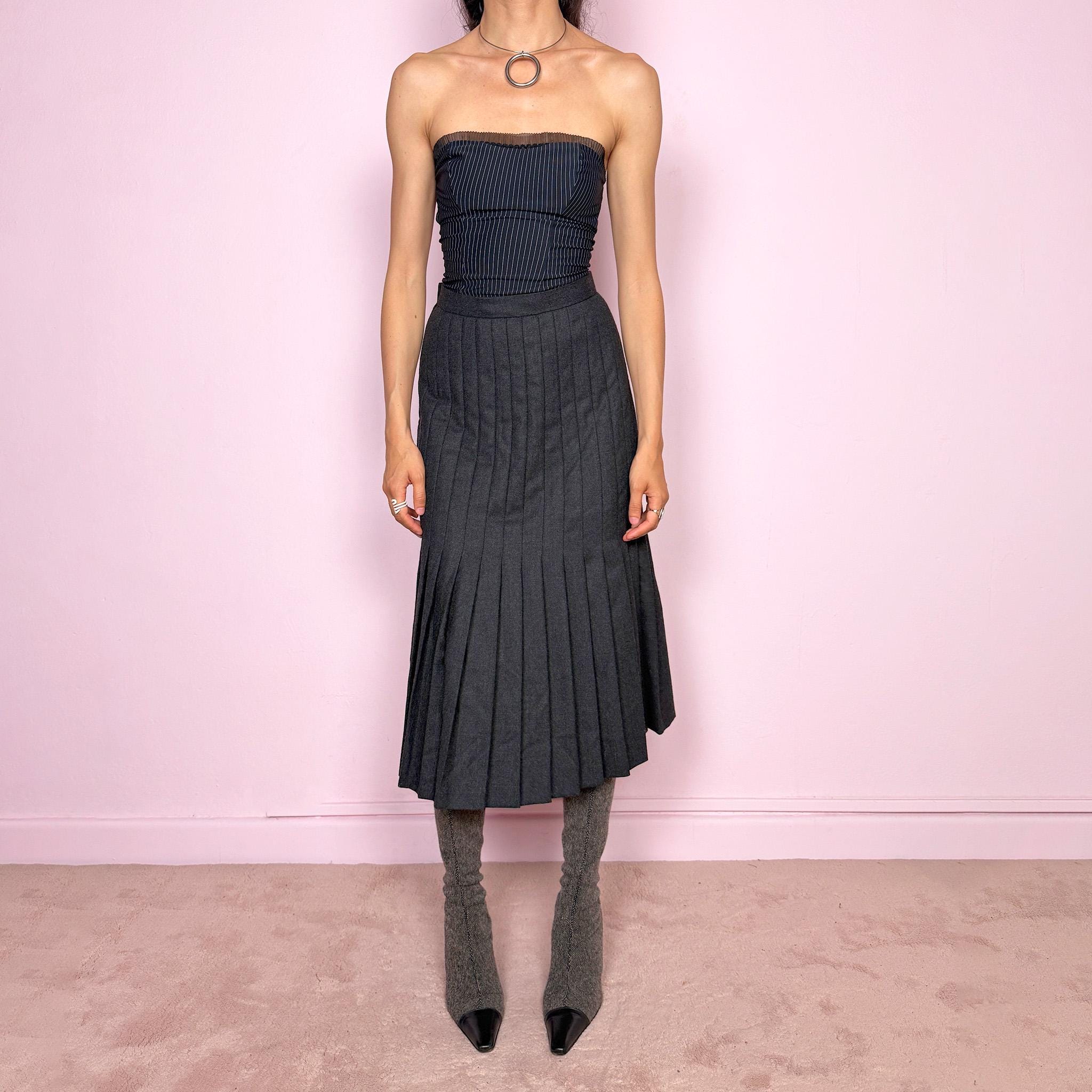 Vintage 90s dark gray midi skirt crafted from a 90% wool and 10% cashmere blend with a full 100% viscose lining. Features all-over pleating, thick non-stretch fabric, and a side zip closure. Fits mid- to high-waisted for size S. A beautifully constructed cold-weather piece combining classic tailoring with an understated avant-garde, minimalist edge. Made by a German brand. Excellent vintage condition.