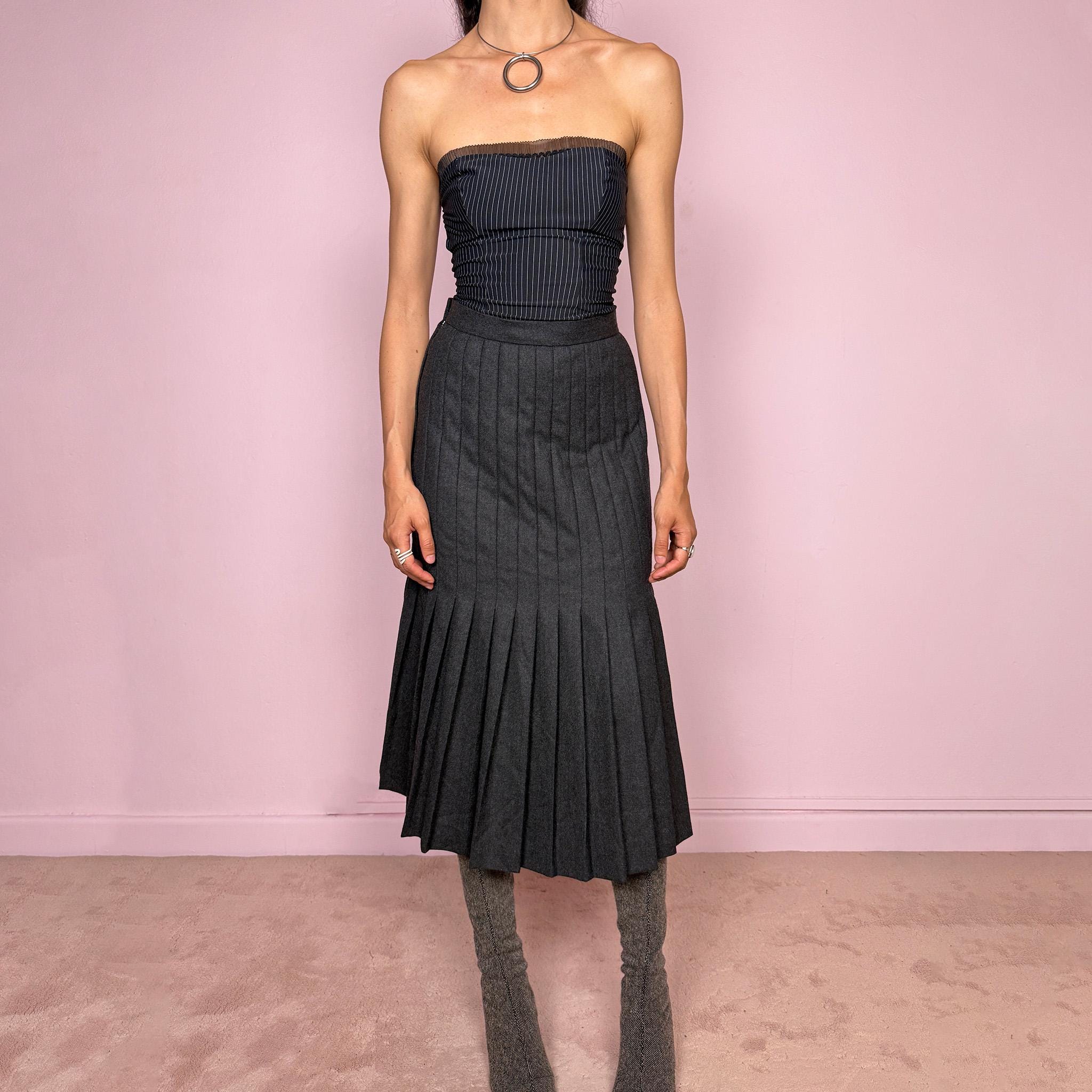 Vintage 90s dark gray midi skirt crafted from a 90% wool and 10% cashmere blend with a full 100% viscose lining. Features all-over pleating, thick non-stretch fabric, and a side zip closure. Fits mid- to high-waisted for size S. A beautifully constructed cold-weather piece combining classic tailoring with an understated avant-garde, minimalist edge. Made by a German brand. Excellent vintage condition.