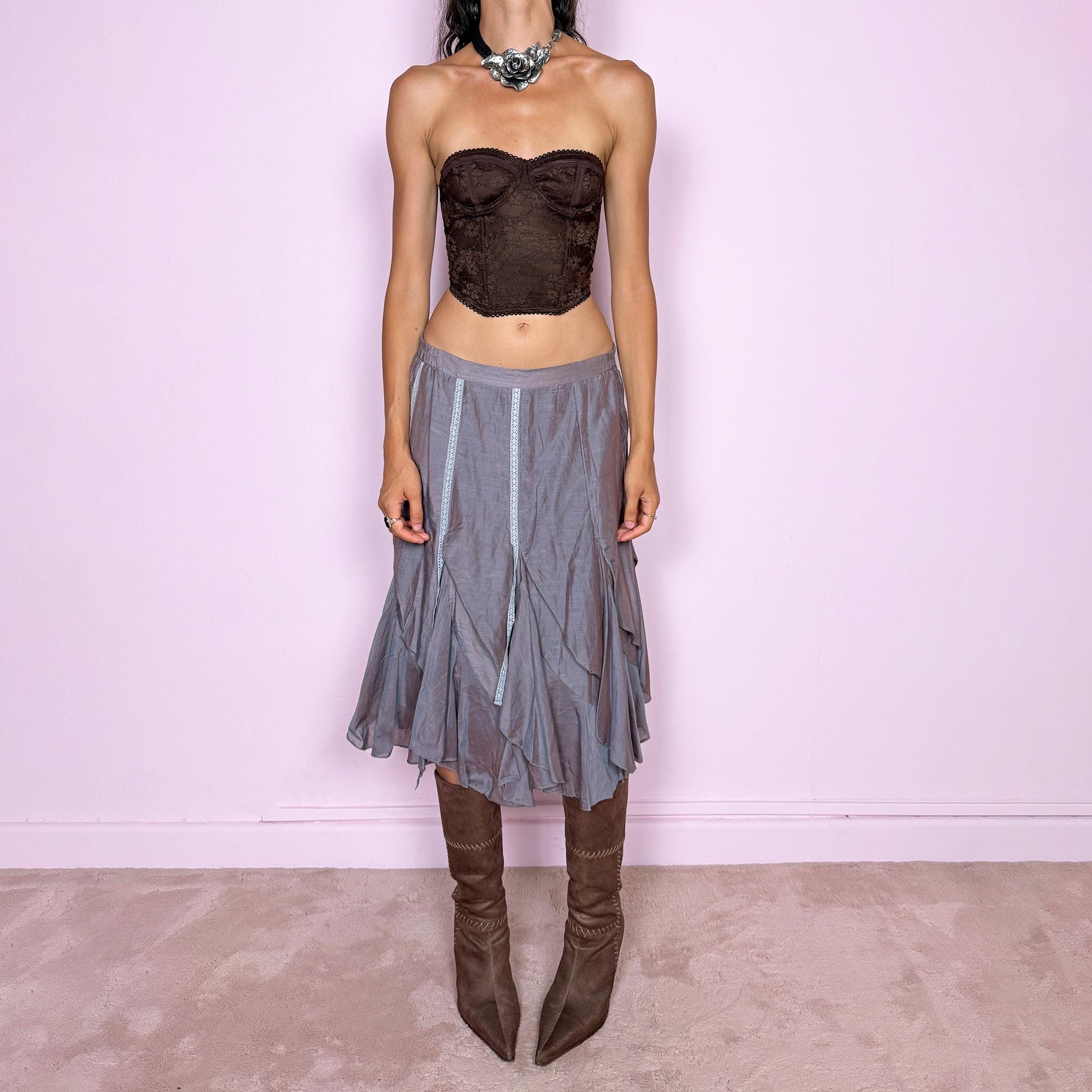 Vintage 2000s bluish-gray iridescent midi skirt featuring a subtle sheen that shifts between dusty blue, gray, and muted mauve tones. Designed with a fluid asymmetric layered construction, curved paneling, delicate lace-trim inserts, and an irregular hem that creates soft movement and a deconstructed silhouette. Perfect for delicate, ethereal styling. Features a back zip closure and no stretch. Can be worn high-waisted for size M or lower-rise for sizes XS–S. Made from 70% cotton and 30% silk