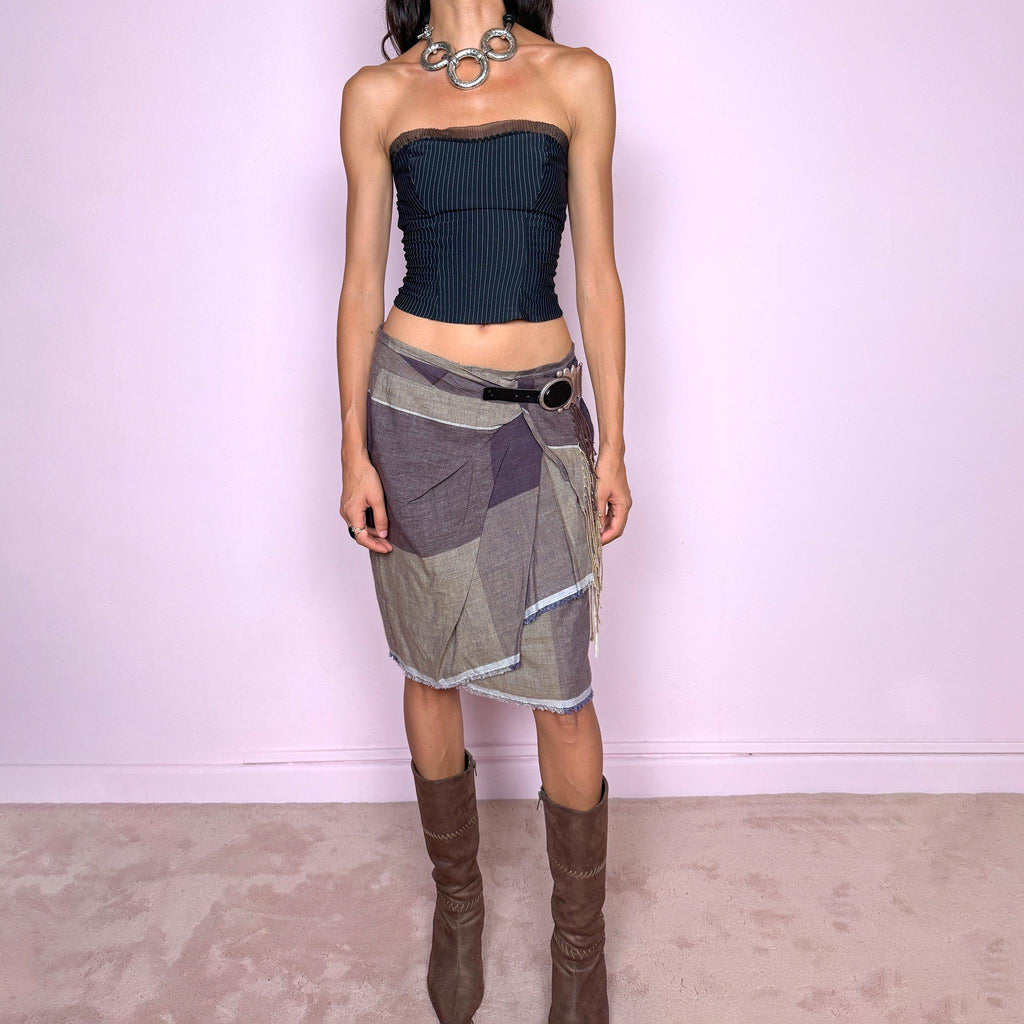 Vintage 2000s wrap midi skirt by Dutch designer Erny van Reijmersdal, crafted from non-stretch 100% linen with a muted oversized plaid pattern in brown, gray, and dusty purple tones. Featuring an asymmetric layered wrap construction with raw frayed edges, contrast paneling, and a dramatic oversized buckle detail set with a large black stone-like centerpiece, silver-tone hardware, and button closure. Finished with cascading side fringe and softly deconstructed folds for an avant-garde feel.