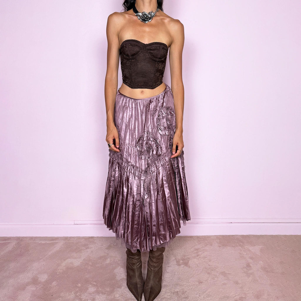 Vintage 2000s dusty mauve metallic midi skirt featuring intricate all-over pleating with a fluid iridescent sheen, sculptural floral appliqué details, and sheer tulle fabric peeking from underneath the hem. Ideal for parties or dreamy, romantic elevated outfits. Can be worn high-waisted for size S or lower on the waist for size XS. From a French brand. Crafted from 100% polyester with no stretch and finished with a side zip closure. Excellent vintage condition.