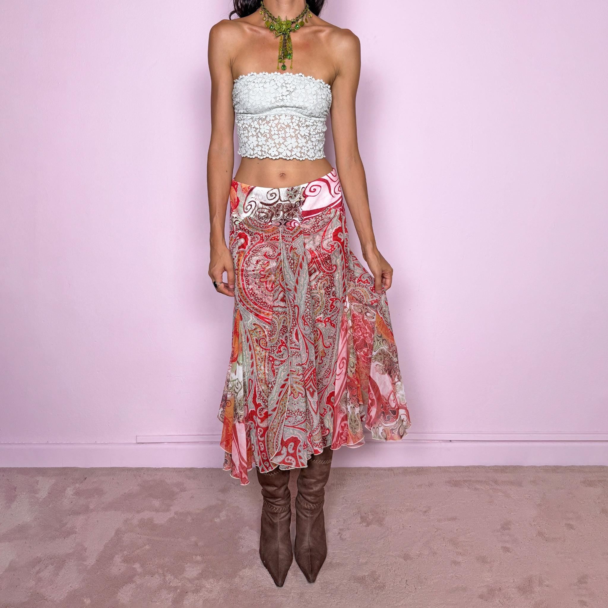 Vintage 2000s 100% silk midi skirt featuring a richly layered red, pink, and earthy-toned paisley and abstract print. The design combines a printed underlayer with a semi-sheer silk overlay, creating depth and movement as the two patterns interact. Cut with multiple godet inserts for a fluid flared silhouette and softly asymmetric hem, giving the skirt a romantic maximalist, art-to-wear feel. Non-stretch with a back zip closure. Can be worn mid-rise for size S or lower on the waist for size XS.