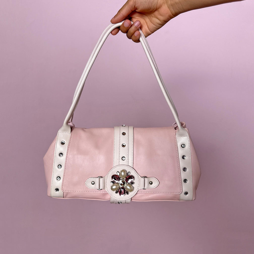 Vintage 2000s shoulder bag, made in Italy from genuine leather in a soft pastel pink and white colorway. Designed in a feminine baguette-inspired silhouette, it features a flap front with magnetic snap button closure, white leather shoulder straps, silver-tone stud details, rhinestone accents and a decorative jeweled front strap with faux pearl and pink rhinestone embellishments. A playful and eye-catching Y2K piece with a romantic rococo coquette feel.