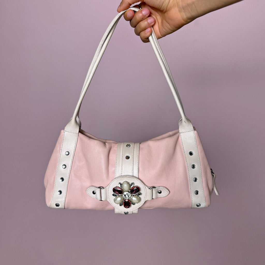 Vintage 2000s Montini pink genuine leather shoulder bag. Features a soft Y2K baguette-inspired silhouette, full top zip closure, magnetic snap button closure, white leather shoulder straps, silver-tone stud details, and a decorative jeweled front strap with faux pearl and pink rhinestone accents. Compact yet eye-catching, with a soft, feminine, and playful 2000s rococo coquette aesthetic. Made in Italy.