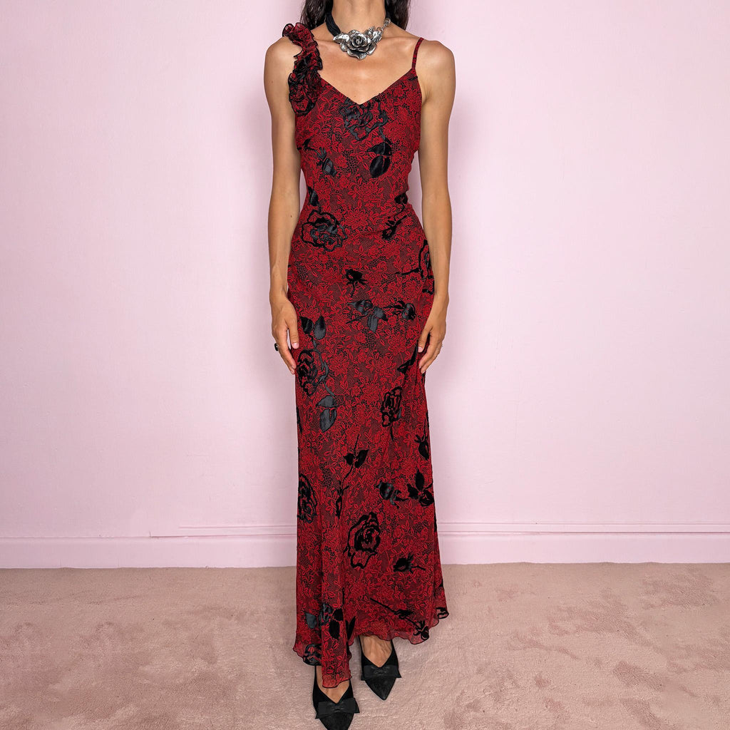 Vintage 2000s red and black floral maxi dress with a fitted silhouette, spaghetti straps, and a dramatic ruffle detail at one shoulder. Designed with a V neckline, long flowing skirt, and black floral motifs over a deep red base, creating a dark romantic evening look. Lightweight with no stretch, a softly semi-sheer outer layer, and black lining, perfect for formal occasions. Composition label is missing, so the exact fabric is unknown. Excellent vintage condition.