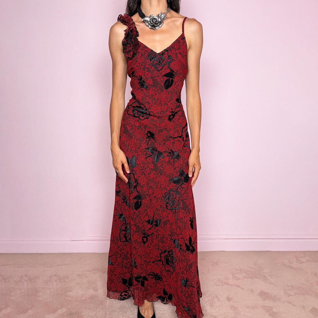 Vintage 2000s red and black floral maxi dress with a fitted silhouette, spaghetti straps, and a dramatic ruffle detail at one shoulder. Designed with a V neckline, long flowing skirt, and black floral motifs over a deep red base, creating a dark romantic evening look. Lightweight with no stretch, a softly semi-sheer outer layer, and black lining, perfect for formal occasions. Composition label is missing, so the exact fabric is unknown. Excellent vintage condition.