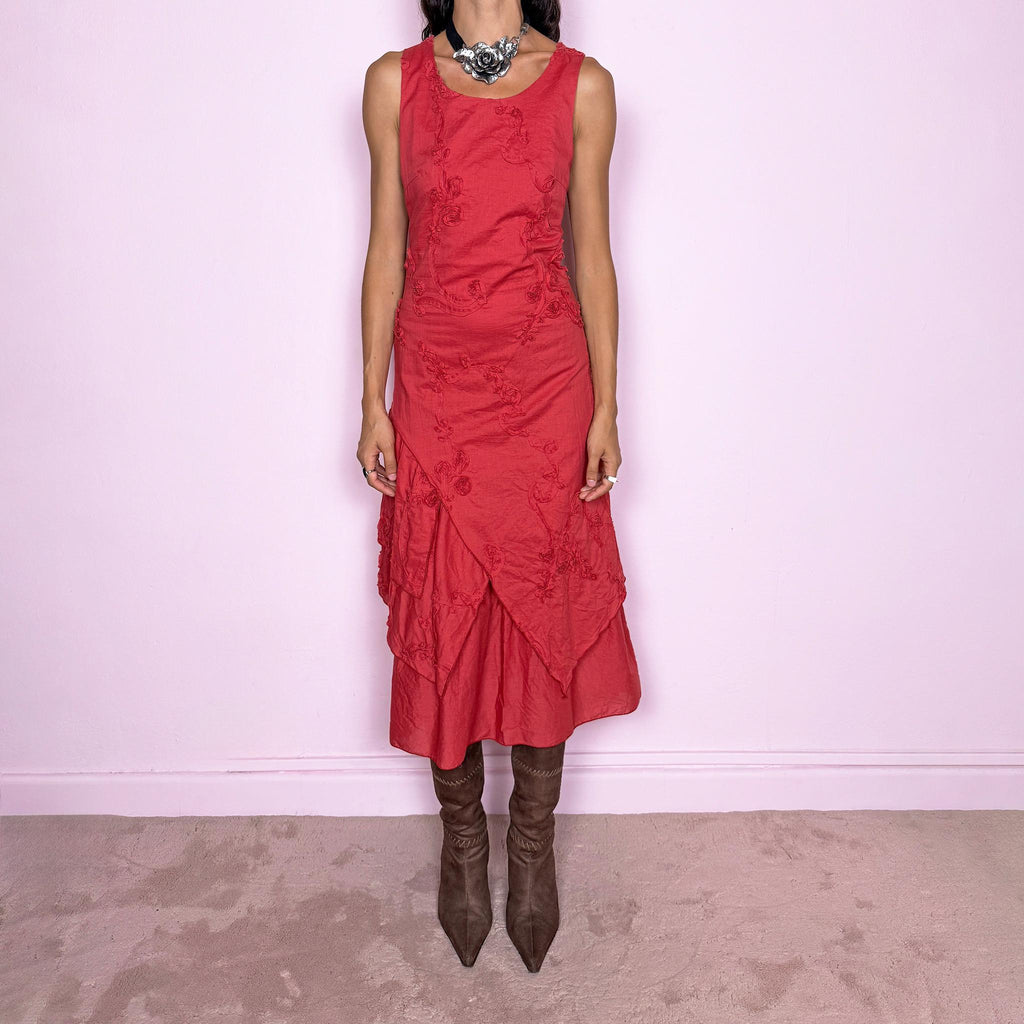 Vintage 2000s muted red midi dress featuring a fitted sleeveless bodice, subtle floral embroidery throughout, layered asymmetric paneling, and a softly flared tiered hem. Finished with a back zip closure. Non-stretch. The slightly faded brick-red tone, textured embroidery, and irregular layered construction give it a rustic, deconstructed aesthetic. Made in France from 100% cotton with a 100% polyester lining, from a French brand. Great vintage condition.