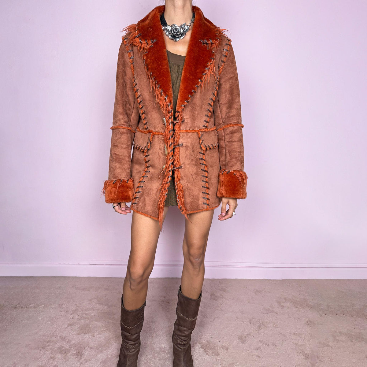 Vintage 2000s rusty terracotta faux-suede coat featuring rich burnt-orange faux-fur trim along the oversized collar and cuffs. Designed with contrast whipstitch detailing throughout, front patch pockets, and toggle-style closures with braided ties down the front. Features a 70s-inspired Penny Lane Y2K aesthetic. The labels are missing, so the exact fabric is unknown. Excellent vintage condition.