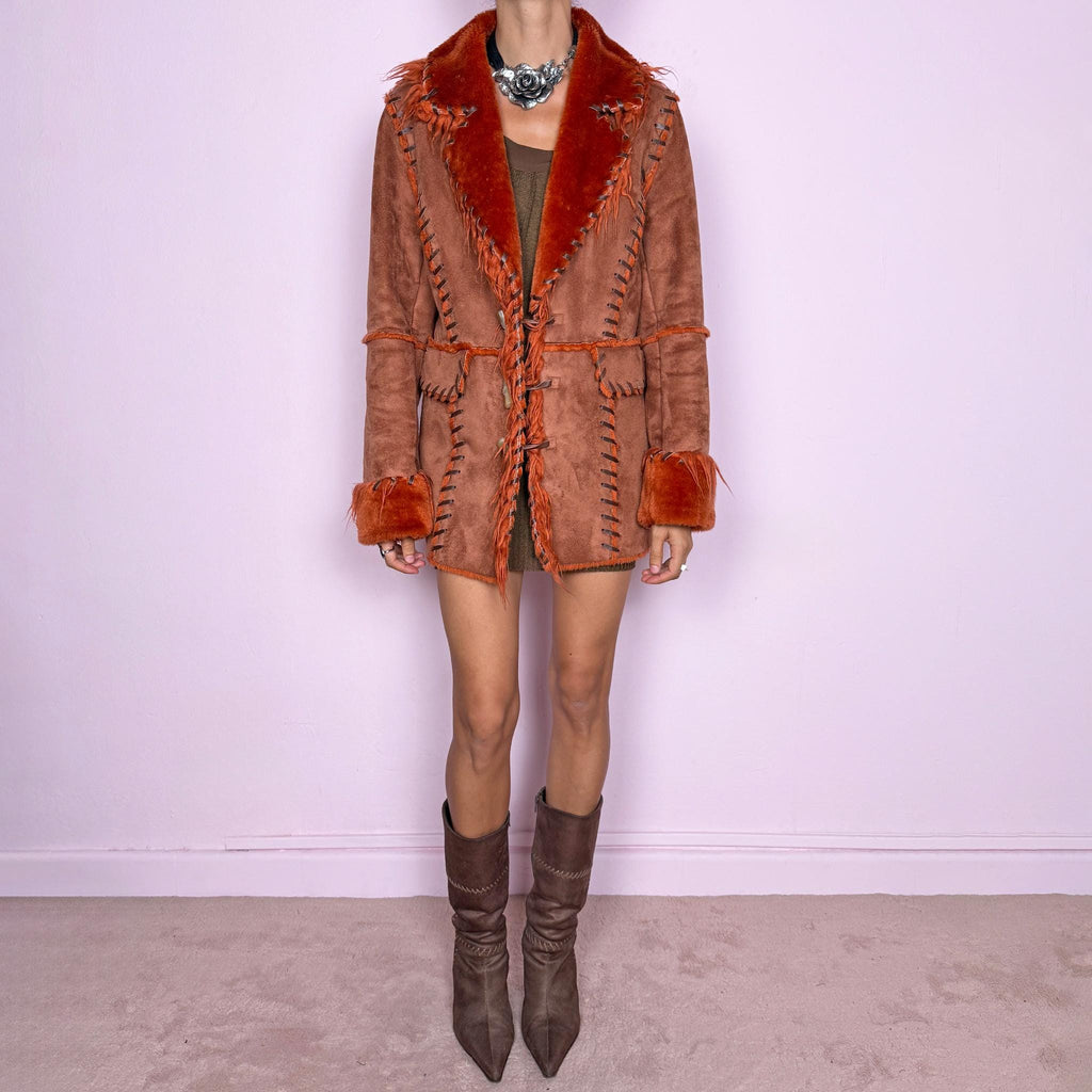 Vintage 2000s rusty terracotta faux-suede coat featuring rich burnt-orange faux-fur trim along the oversized collar and cuffs. Designed with contrast whipstitch detailing throughout, front patch pockets, and toggle-style closures with braided ties down the front. Features a 70s-inspired Penny Lane Y2K aesthetic. The labels are missing, so the exact fabric is unknown. Excellent vintage condition.