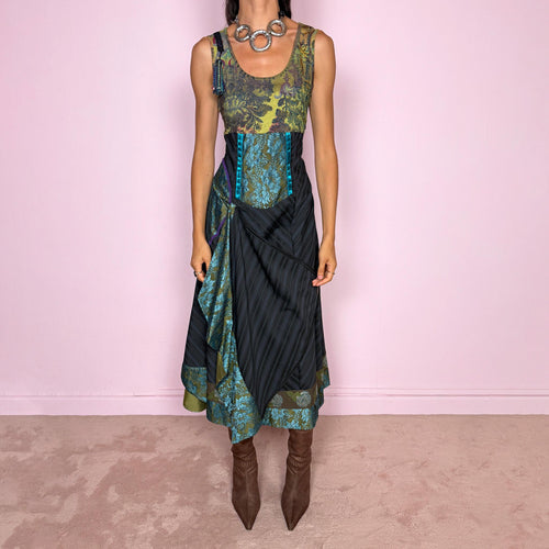 Vintage 2000s midi dress designed with a dramatic, medieval-inspired avant-garde silhouette. It features a graphic bust panel with green multicolored abstract artwork, a fitted waist with blue lace panels, a side zip closure, and a flowing asymmetric skirt with mixed striped fabrics, contrast trims, and layered draped sections that create sculptural movement. A rare fantasy statement piece with a theatrical baroque feel.