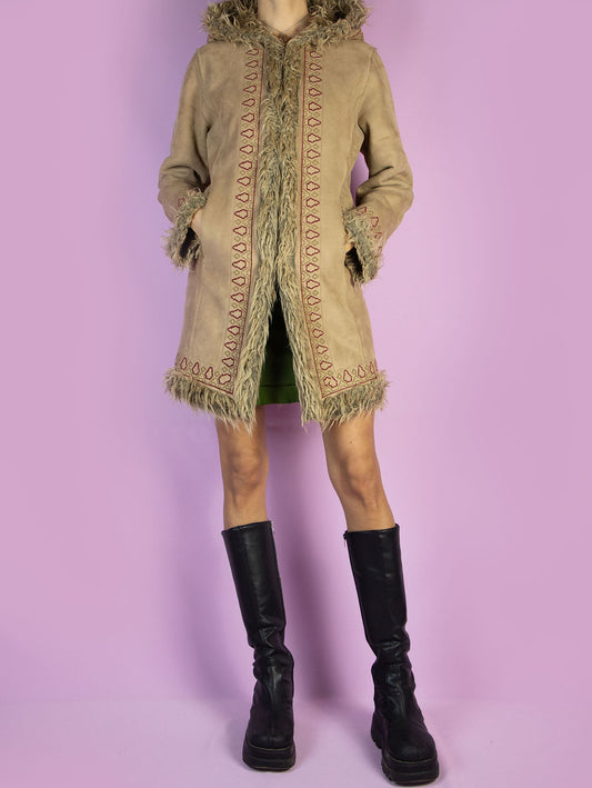 The Y2K Beige Afghan Hooded Coat is a vintage 2000s Penny Lane-style winter jacket crafted from light brown faux suede with shaggy faux fur trim on the hood, cuffs, and interior. Featuring intricate embroidered detailing, front pockets, and hook-and-eye closures, this warm mid-length coat brings boho drama and retro charm to cold-weather outfits. A standout piece for winter layering with a romantic, nostalgic edge.