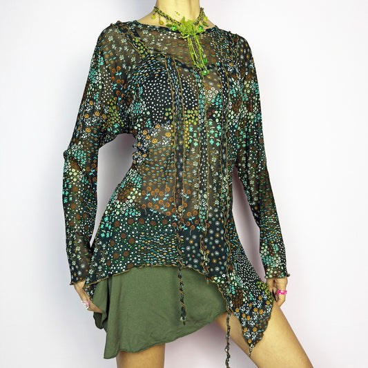 The Y2K Black Asymmetric Mesh Top is a vintage 2000s statement piece featuring semi-sheer mesh fabric with a floral and geometric print. Designed with an edgy asymmetric cut and delicate lettuce hem detailing, this top embodies a deconstructed aesthetic with a fairy grunge-inspired touch. The lightweight, stretchy fabric makes it perfect for layering, making it an ideal choice for summer avant-garde outfits. Excellent vintage condition.