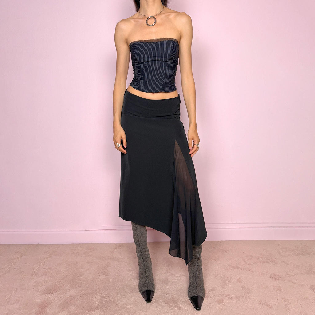Vintage 2000s black midi skirt with an avant-garde deconstructed look. Features a pointed asymmetric hem, semi-sheer mesh panel detail, side zip closure, and a smooth no-stretch fit with a fluid draped silhouette. Perfect for dark styling and evening events. Can be worn high waisted for S or lower rise for XS/XXS. Made from a polyester elastane blend. Excellent vintage condition.