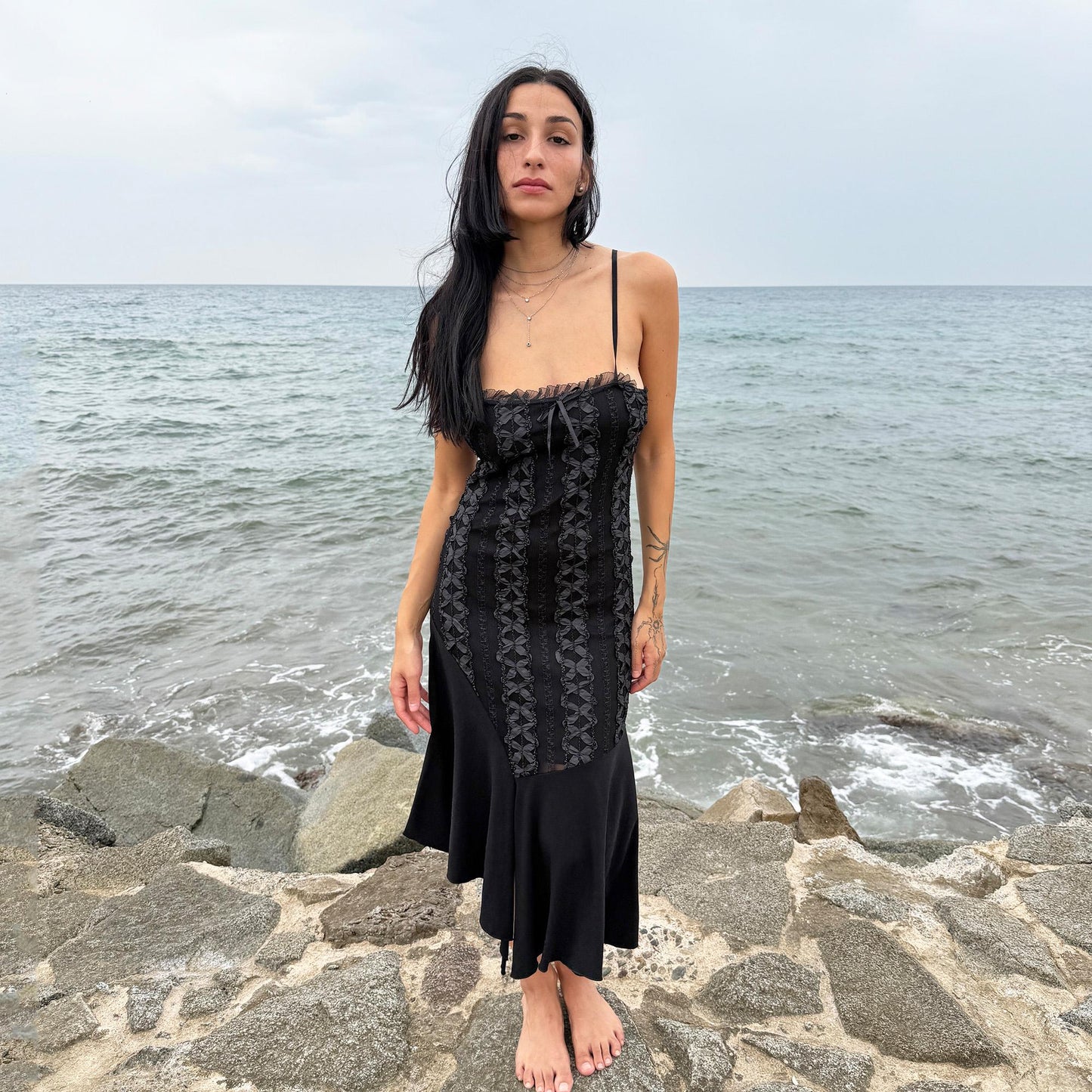 This vintage 2000s black midi dress features an asymmetrical handkerchief hem with whimsical flow and delicate mesh panel details through the bodice. Crafted in France from a stretchy polyester blend, it hugs the figure while allowing movement. A romantic dark piece with fairy, witchy, and night-party energy—perfect for Y2K alternative styling. Made from polyester stretch blend. Excellent vintage condition.