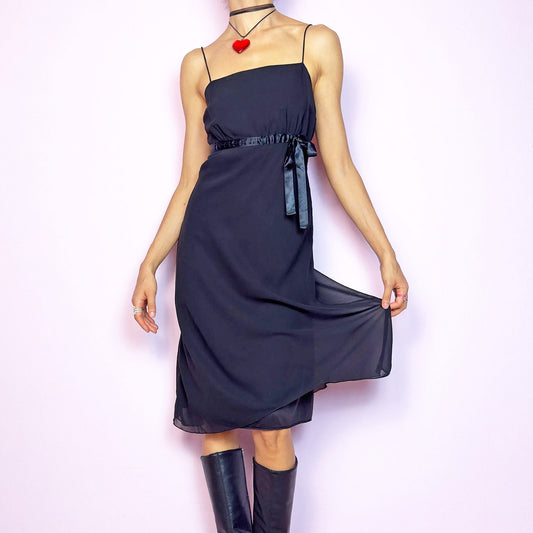 The Y2K Black Slip Midi Dress is a vintage 2000s dreamy minimalist piece featuring a lightweight sheer overlay, spaghetti straps, a flattering empire waist with a satin tie, and a classic midi silhouette. The lightweight, flowy fabric creates beautiful movement, making it perfect for party looks and romantic evenings. Classic, versatile, and effortlessly chic. Great vintage condition.