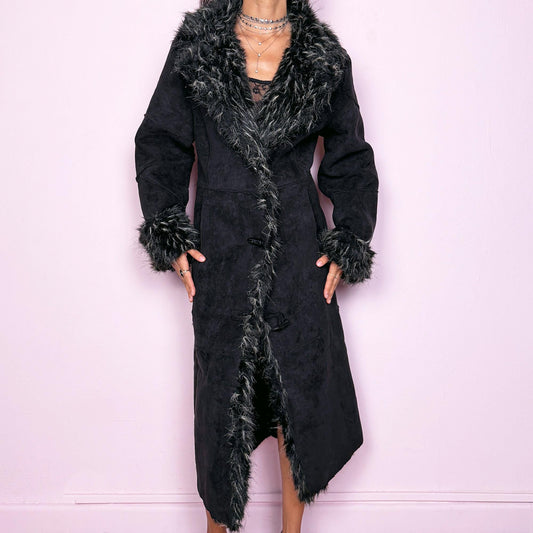 This vintage 2000s black maxi Penny Lane coat features a plush faux suede shell with dramatic black-and-beige faux fur trim at the collar and cuffs. Designed with toggle closures and side pockets, it offers warmth and structure while exuding bohemian gothic elegance. The long silhouette and textured fur detailing create a striking statement—perfect for winter nights, city wear, or whimsical Y2K layering. Made from polyester acrylic blend. Excellent vintage condition.