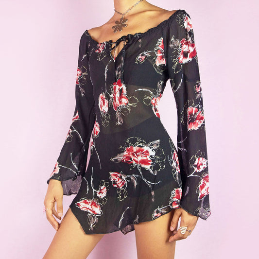 The Y2K Floral Off-Shoulder Blouse is a vintage 2000s top featuring a sheer fabric with a floral print. This blouse has an off-the-shoulder neckline with a tie detail, flared sleeves, and side slits at the hem. Its asymmetric hemline adds a romantic and bohemian vibe. Perfect for casual wear or summer events.