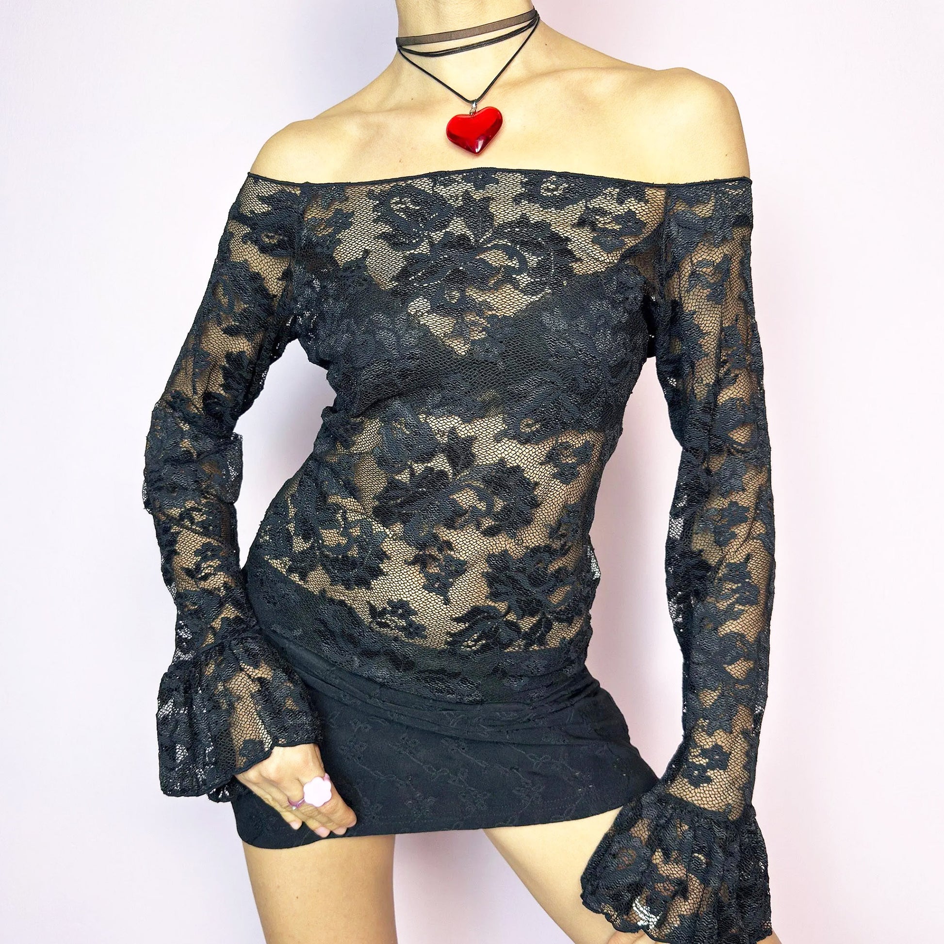 The Y2K Black Ruffle Lace Top is a vintage 2000s piece featuring a sheer mesh floral pattern with an off-the-shoulder neckline and dramatic ruffle bell sleeves. The fitted silhouette enhances its romantic and edgy vibe, making it ideal for layering or wearing on its own for a night-out look. Lightweight and breathable, perfect for summer styling. Made in Spain. Excellent vintage condition.