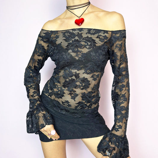 The Y2K Black Ruffle Lace Top is a vintage 2000s piece featuring a sheer mesh floral pattern with an off-the-shoulder neckline and dramatic ruffle bell sleeves. The fitted silhouette enhances its romantic and edgy vibe, making it ideal for layering or wearing on its own for a night-out look. Lightweight and breathable, perfect for summer styling. Made in Spain. Excellent vintage condition.