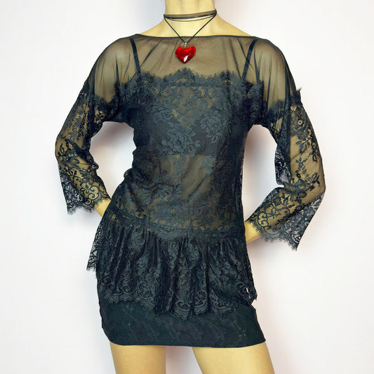 The Y2K Black Lace Peplum Top is a vintage 2000s piece featuring sheer mesh panels, floral lace detailing, and a flattering peplum hem. Designed with three-quarter length sleeves and a boat neckline for an elegant yet sultry silhouette. Perfect for layering or styling for a night out. Stretchy and lightweight for a comfortable fit. Excellent vintage condition.