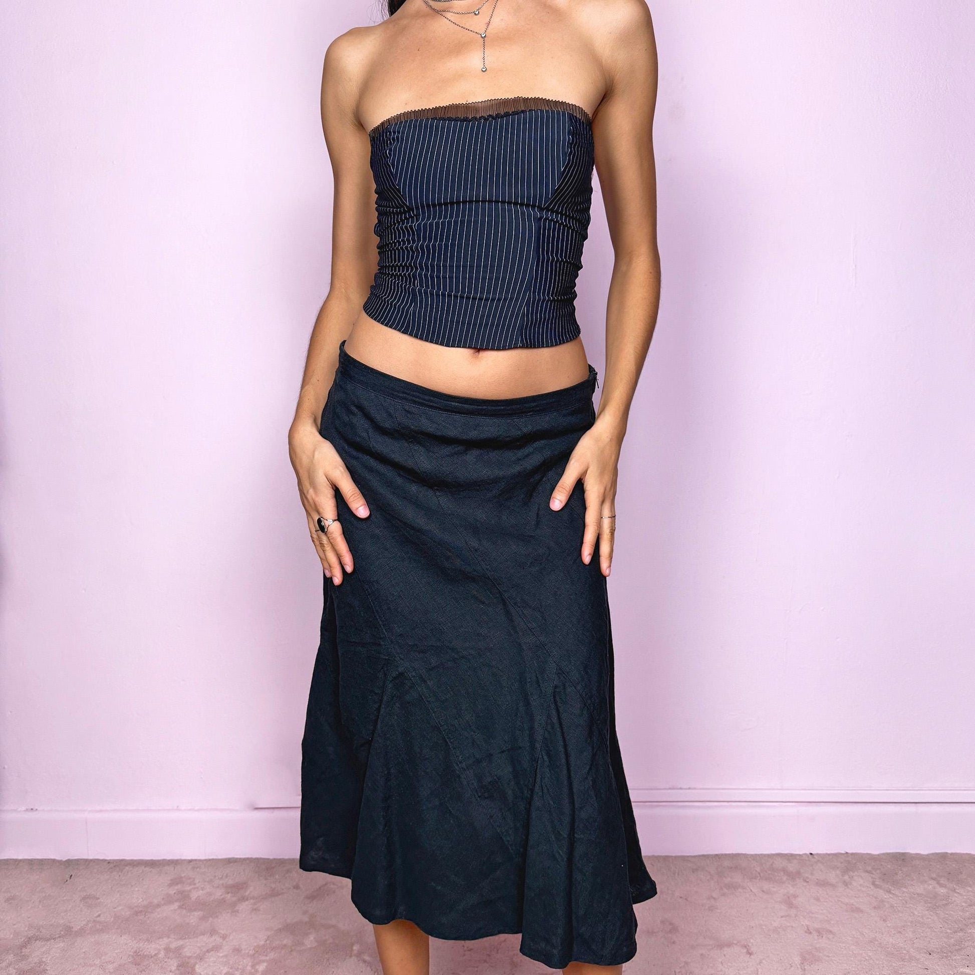 This vintage black flared linen midi skirt offers a timeless, structured silhouette with a side zipper closure and no stretch. Can be worn low-rise for size XS/S or high-rise for size M, adapting easily to different fits. A refined minimalist piece ideal for elegant summer styling, workwear, or casual sophistication. Made from 100% linen non-stretch. Great vintage condition.