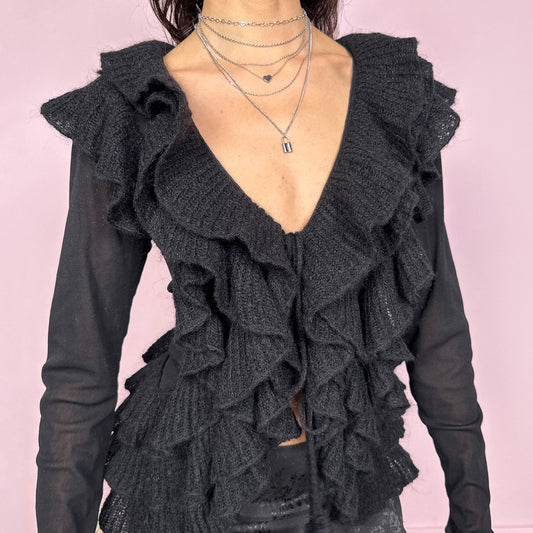 Vintage 2000s avant garde black mesh long sleeve tie front top featuring cascading knit ruffles over a sheer polyamide base, creating a dark romantic silhouette with soft texture and fluid movement. Ruffles are crafted from 30% kid mohair with a polyamide acrylic blend. Ideal for evening, night, party, or statement layering. Made in Italy by a French brand. Excellent vintage condition.
