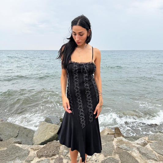 This vintage 2000s black midi dress features an asymmetrical handkerchief hem with whimsical flow and delicate mesh panel details through the bodice. Crafted in France from a stretchy polyester blend, it hugs the figure while allowing movement. A romantic dark piece with fairy, witchy, and night-party energy—perfect for Y2K alternative styling. Made from polyester stretch blend. Excellent vintage condition.