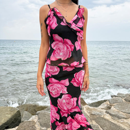 This vintage 2000s two-piece set features a pleated black fabric with oversized pink rose print. The trumpet godet midi skirt with elastic waist pairs with a cami top detailed by a ruffled neckline. A romantic feminine coord, ideal for summer promenades, Mediterranean cruises, or sunset parties. A collectible statement in girly Y2K style. Made in France from a polyester blend. Excellent vintage condition.