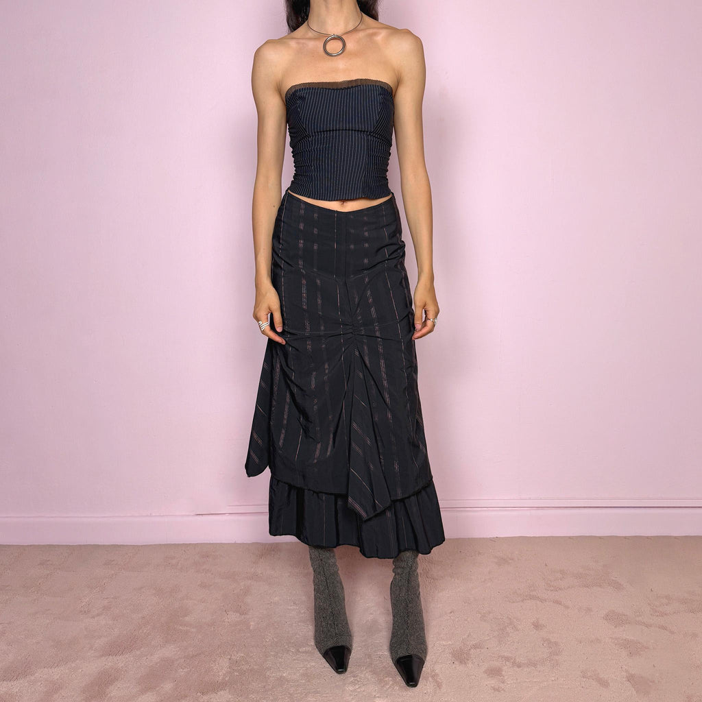Vintage 2000s black midi skirt with pink pinstripes, a layered deconstructed silhouette, ruched details, and ruffled hem. This dark avant-garde piece has a structured no-stretch fit with back zip closure. Can be worn high waisted for size S or lower rise for XXS and XS. Made in France from a cotton, polyamide, and polyester blend. Great vintage condition.