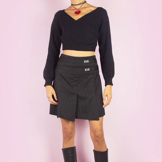 The Y2K Pinstripe Pleated Mini Skirt is a vintage 2000s piece featuring a classic pinstripe pattern with pleated detailing in black. Designed with a mid-rise fit, mini length, and side zipper closure, it’s perfect for office-to-evening transitions or casual chic outfits.