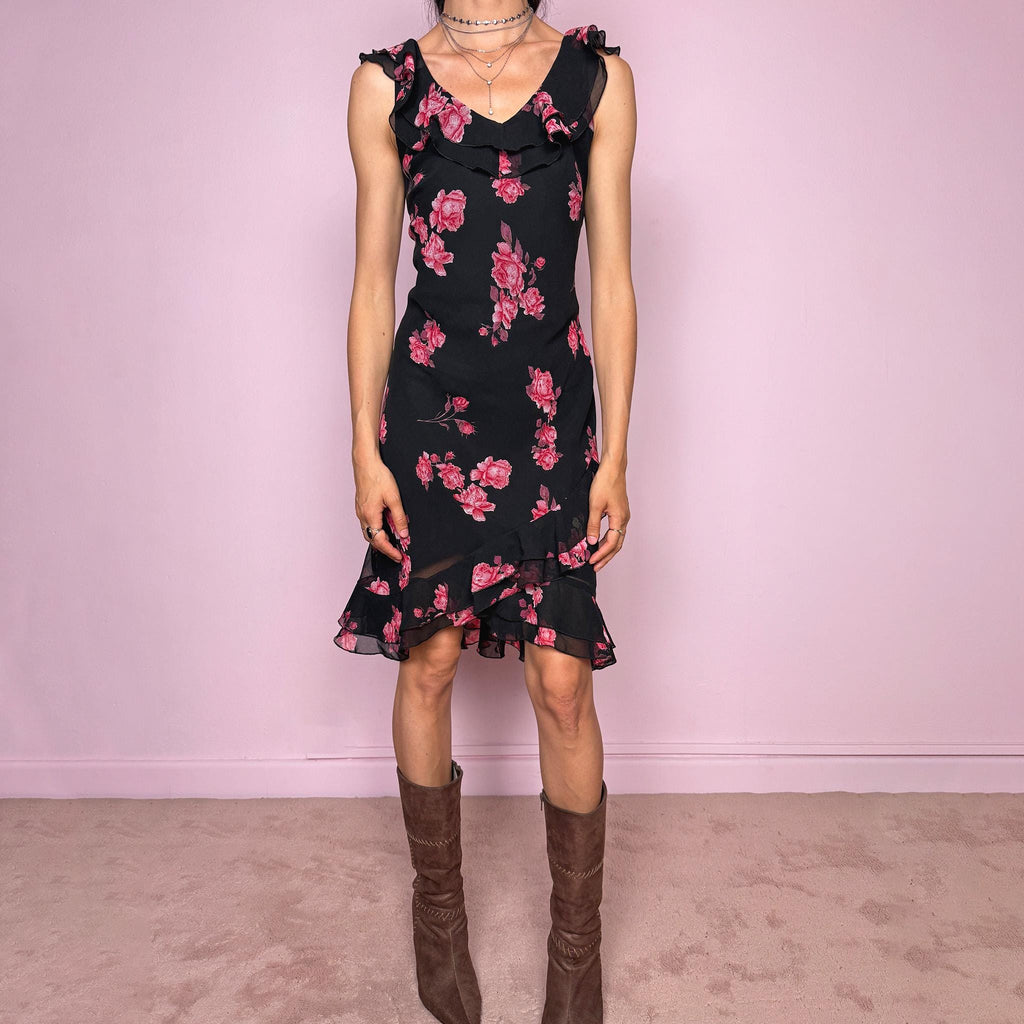 Vintage 2000s black floral mini dress with a romantic 90s feel, pink rose print, sleeveless fitted silhouette, V neckline, ruffled bust and straps, and an asymmetric layered ruffle tulip hem. Ideal for feminine spring and summer looks. Made by a French brand. Great vintage condition.