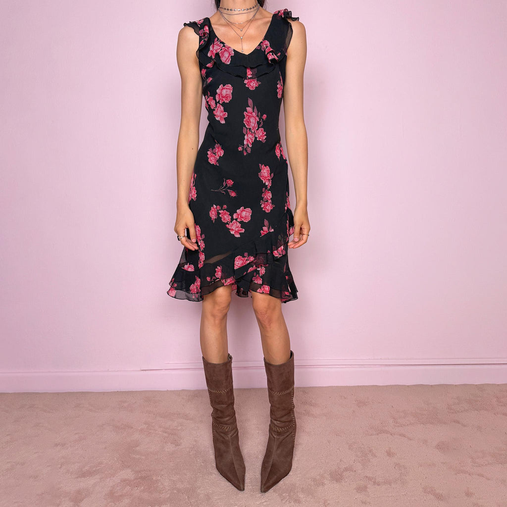 Vintage 2000s black floral mini dress with a romantic 90s feel, pink rose print, sleeveless fitted silhouette, V neckline, ruffled bust and straps, and an asymmetric layered ruffle tulip hem. Ideal for feminine spring and summer looks. Made by a French brand. Great vintage condition.