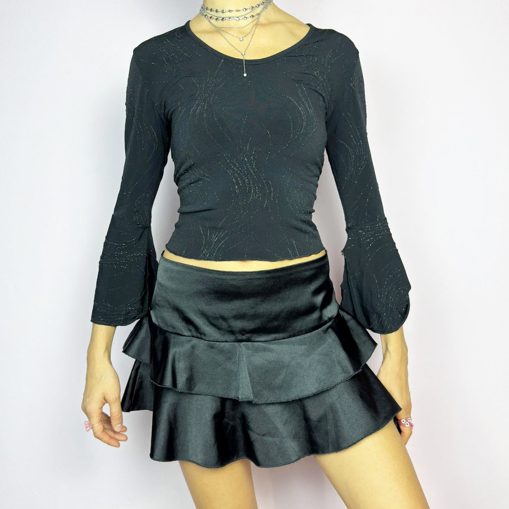 The Y2K Black Ruffle Satin Mini Skirt is a vintage 2000s piece made from a sleek satin-style stretchy fabric featuring layered ruffles, low rise design and a side zipper closure. Ideal for a night-out outfit. Great vintage condition.