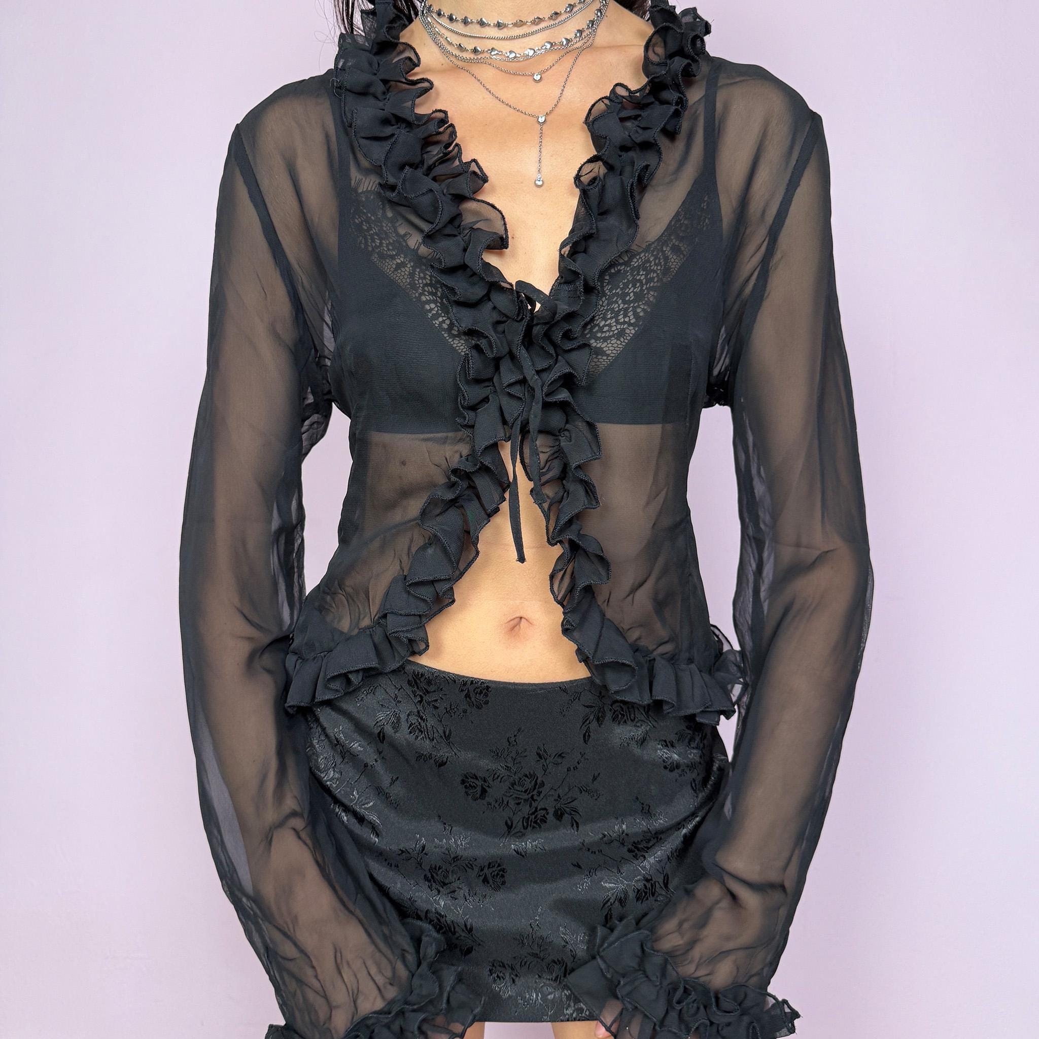 This vintage 2000s black semi-sheer top features long sleeves, a tie-front closure and a gathered ruffle neckline with matching ruffled cuffs. The lightweight fabric drapes softly with no stretch, creating an elegant dark romance look perfect for party nights, layering, or styling as a bolero-style blouse. A flattering statement piece that elevates evening outfits. Excellent vintage condition.