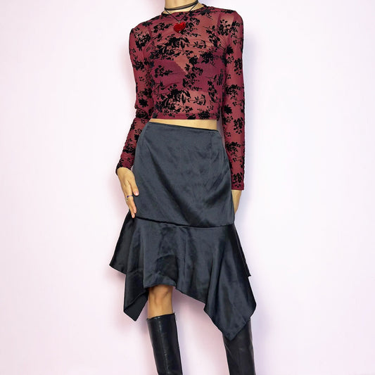 The Y2K Black Satin Asymmetric Skirt is a vintage 2000s stylish piece, featuring a satin-like finish with an asymmetrical handkerchief hemline for a dramatic flair and a size zipper closure. Perfect choice for party nights and chic night-out looks. Great vintage condition.