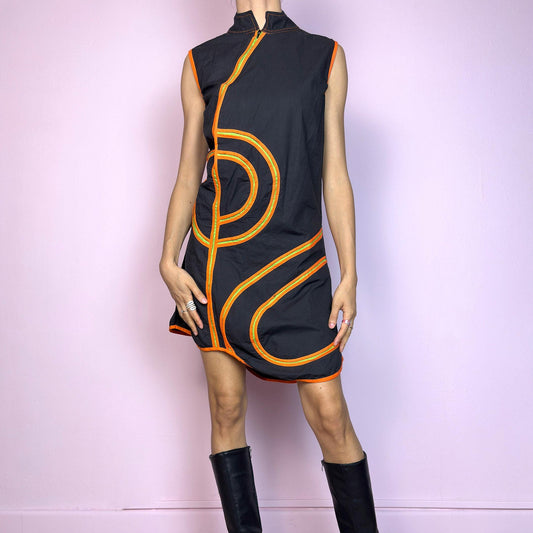 This vintage 2000s sleeveless mini dress is cut from black cotton with bold orange contrast piping and a futuristic mod design. Features a mock neck, sculptural seams, and a half front zipper closure. Has no stretch, designed for summer impact. A cyber-graphic Y2K silhouette with bold, kinetic energy—perfect for parties, raves, or standout street style. Great vintage condition.