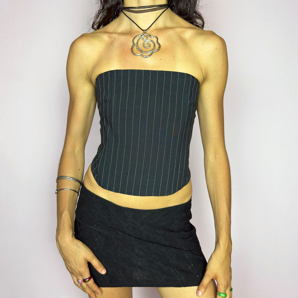 This vintage 2000s pinstripe corset top features a strapless silhouette with boning structure and a back zip closure for a sharp, tailored fit. Crafted in black with fine white stripes, it blends soft tailoring with city girl allure. Elegant yet subversive, it's ideal for cocktail hours, office party nights, or elevated downtown styling. A Y2K structured piece that channels confident, refined edge. Excellent vintage condition.