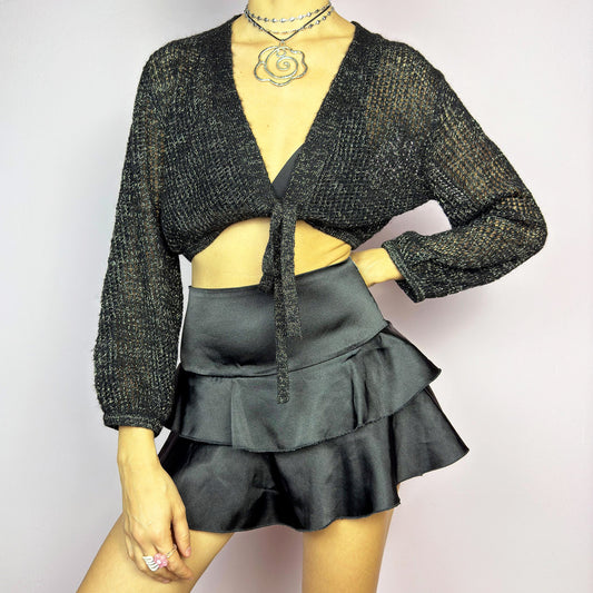 This Y2K Black Tie Front Cardigan is a vintage 2000s piece featuring a lightweight open-knit design with a subtle metallic shimmer, a cropped fit and long sleeves. Perfect for layering and ideal for night-out or casual outfits. Excellent vintage condition.