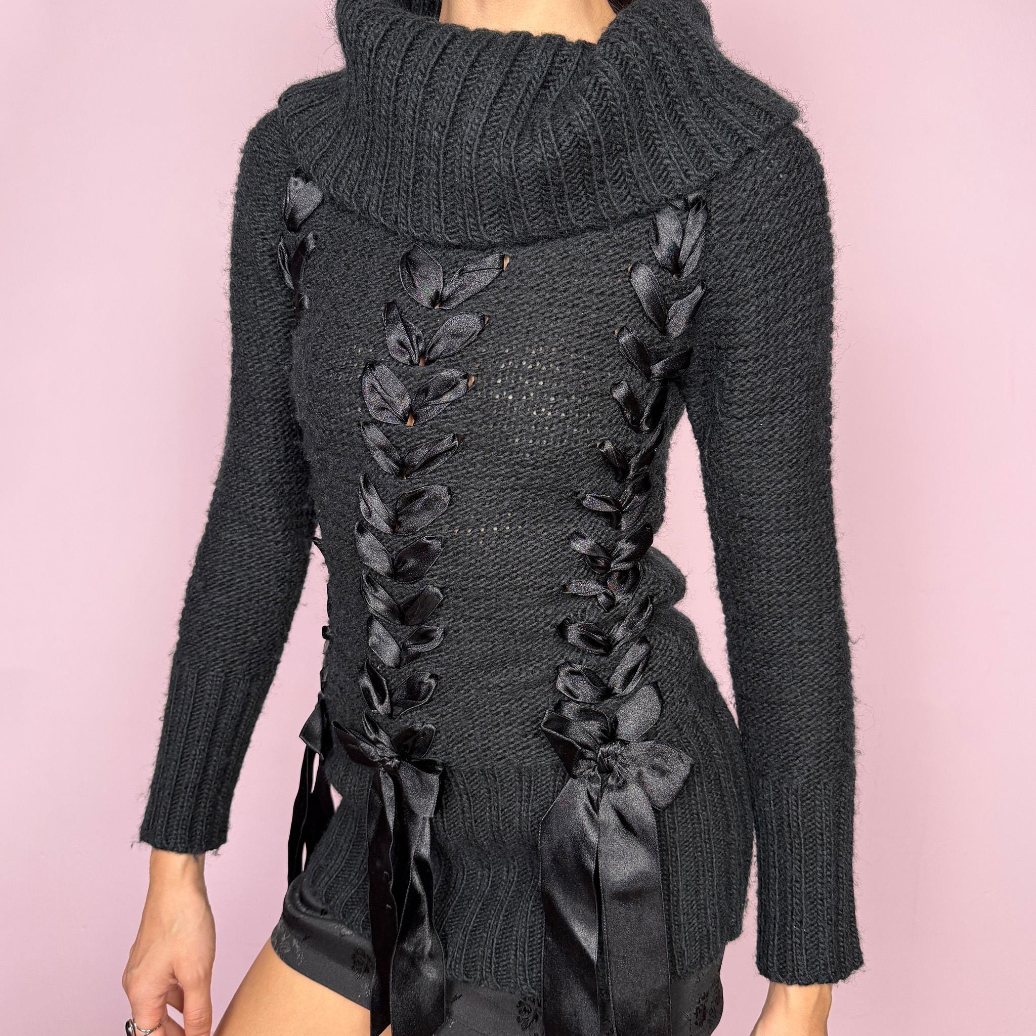 Dark coquette vintage 2000s black turtleneck chunky knit sweater with long sleeves. Features lace-up satin-style ribbon details creating a romantic, unique statement design. Soft yet structured with a fitted silhouette, perfect for winter layering or styled as a standout piece. Stretchy 60% acrylic and 40% wool blend made by a French brand. Great vintage condition.