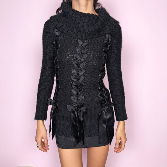 Dark coquette vintage 2000s black turtleneck chunky knit sweater with long sleeves. Features lace-up satin-style ribbon details creating a romantic, unique statement design. Soft yet structured with a fitted silhouette, perfect for winter layering or styled as a standout piece. Stretchy 60% acrylic and 40% wool blend made by a French brand. Great vintage condition.