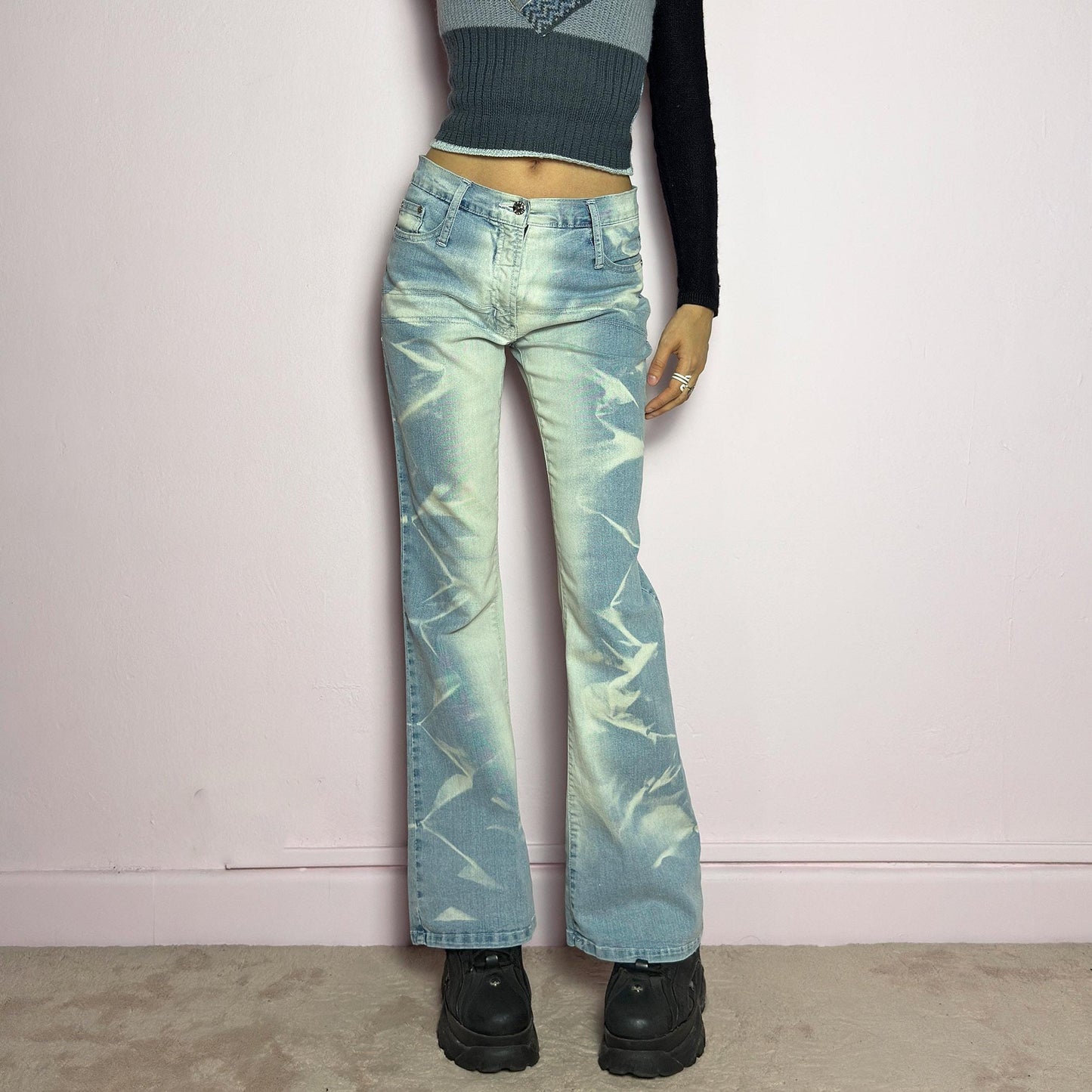The Y2K Bleached Flare Jeans are a vintage 2000s statement piece featuring a light-wash denim with a bold bleached abstract pattern for a deconstructed, experimental look. Designed with a flattering mid-rise fit, flared legs, button and zipper closure, and pockets, these jeans are a perfect blend of edgy and playful aesthetics. Ideal for standout casual outfits. adult world shop