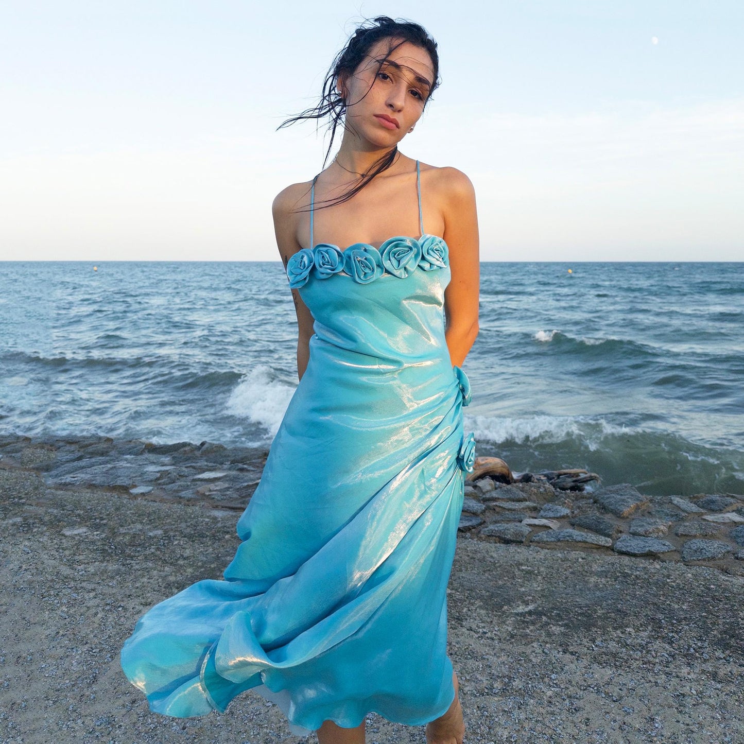 The vintage 2000s blue slip dress is a French-made fantasy with sculptural rosette appliqué along the bust and ruched side detail. Its iridescent finish and fluid midi length evoke a dreamy softness, perfect for proms, summer weddings, or romantic evenings. The silhouette is both delicate and structured, capturing quiet glamour with fairytale allure. A romantic Y2K archive crafted from a shimmering non-stretch fabric. Great vintage condition.