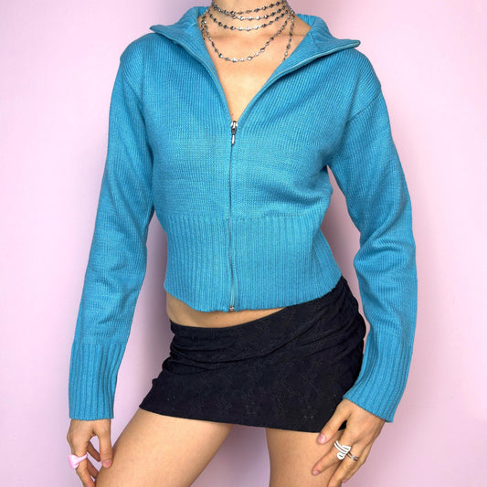 The Y2K Blue Zip Cardigan is a vintage 2000s cropped zip-up knit featuring a vibrant aqua blue tone, a flattering fitted silhouette, a wide collar, and ribbed hem and cuffs. Ideal for layering or adding a pop of color to your casual autumn outfits. Excellent vintage condition. adult world shop