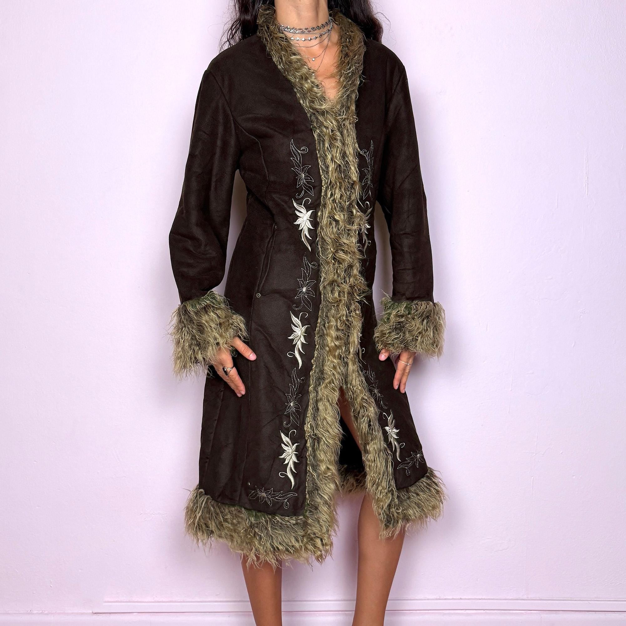 This vintage 2000s dark brown Penny Lane coat features beige faux fur trim at the collar, cuffs, and hem, with intricate floral embroidery along the front. Crafted from soft faux suede with pockets and dual snap-and-hook closure, it embodies the whimsical 70s Afghan-inspired Y2K aesthetic. Warm and romantic—perfect for fairycore, boho, and forest muse styling. Made from polyester faux suede and faux fur. Great vintage condition.