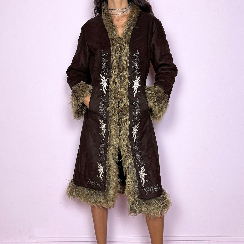 This vintage 2000s dark brown Penny Lane coat features beige faux fur trim at the collar, cuffs, and hem, with intricate floral embroidery along the front. Crafted from soft faux suede with pockets and dual snap-and-hook closure, it embodies the whimsical 70s Afghan-inspired Y2K aesthetic. Warm and romantic—perfect for fairycore, boho, and forest muse styling. Made from polyester faux suede and faux fur. Great vintage condition.