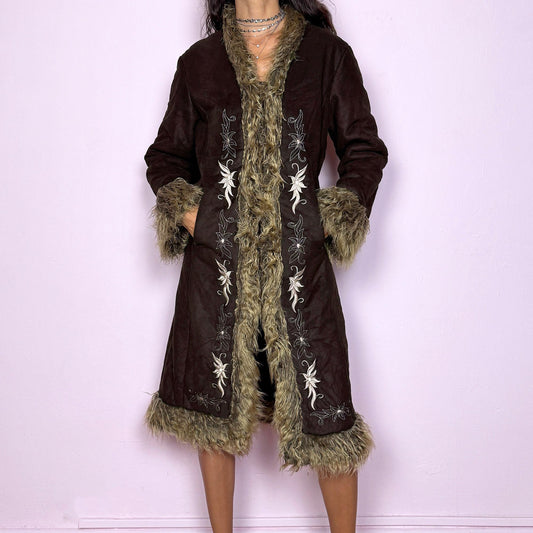 This vintage 2000s dark brown Penny Lane coat features beige faux fur trim at the collar, cuffs, and hem, with intricate floral embroidery along the front. Crafted from soft faux suede with pockets and dual snap-and-hook closure, it embodies the whimsical 70s Afghan-inspired Y2K aesthetic. Warm and romantic—perfect for fairycore, boho, and forest muse styling. Made from polyester faux suede and faux fur. Great vintage condition.