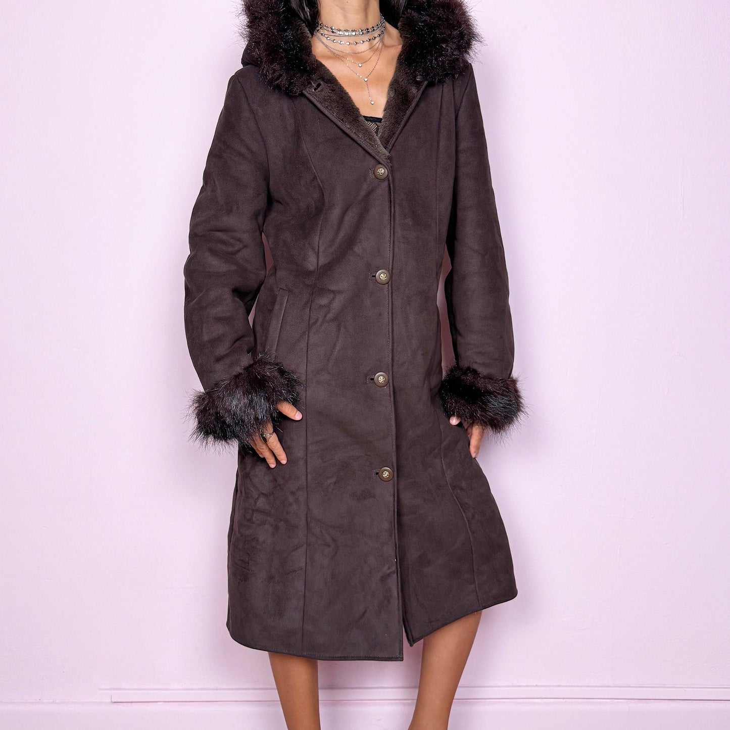 This stunning vintage 2000s dark brown-purple faux suede long coat features a hooded Penny Lane cut with a plush faux fur collar, cuffs, and full interior. It also includes a button front and pockets. Its rich tone evokes dark whimsy and fairycore night energy, blending goth romance with bohemian warmth. Made from faux suede with faux fur lining. Great vintage condition.