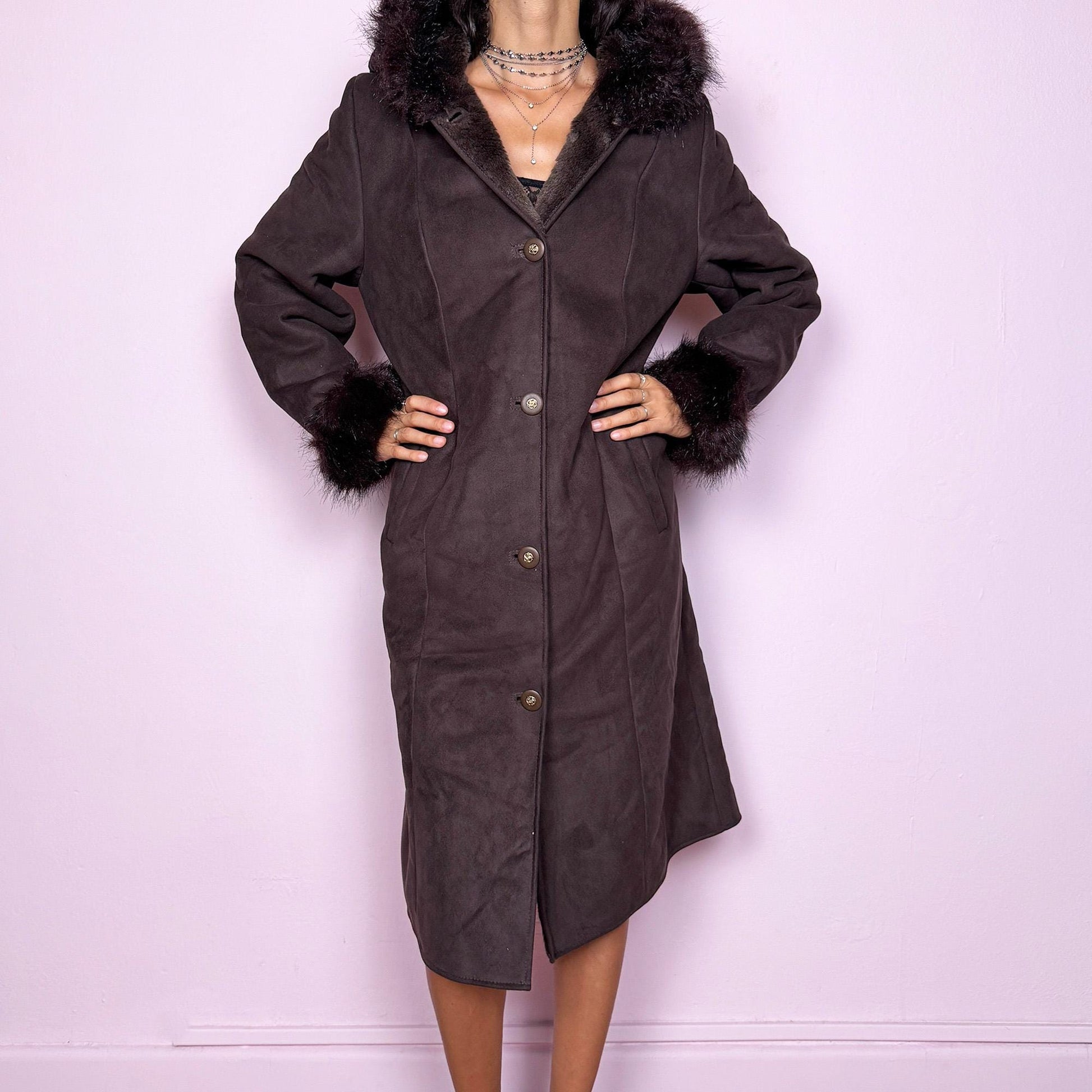 This stunning vintage 2000s dark brown-purple faux suede long coat features a hooded Penny Lane cut with a plush faux fur collar, cuffs, and full interior. It also includes a button front and pockets. Its rich tone evokes dark whimsy and fairycore night energy, blending goth romance with bohemian warmth. Made from faux suede with faux fur lining. Great vintage condition.